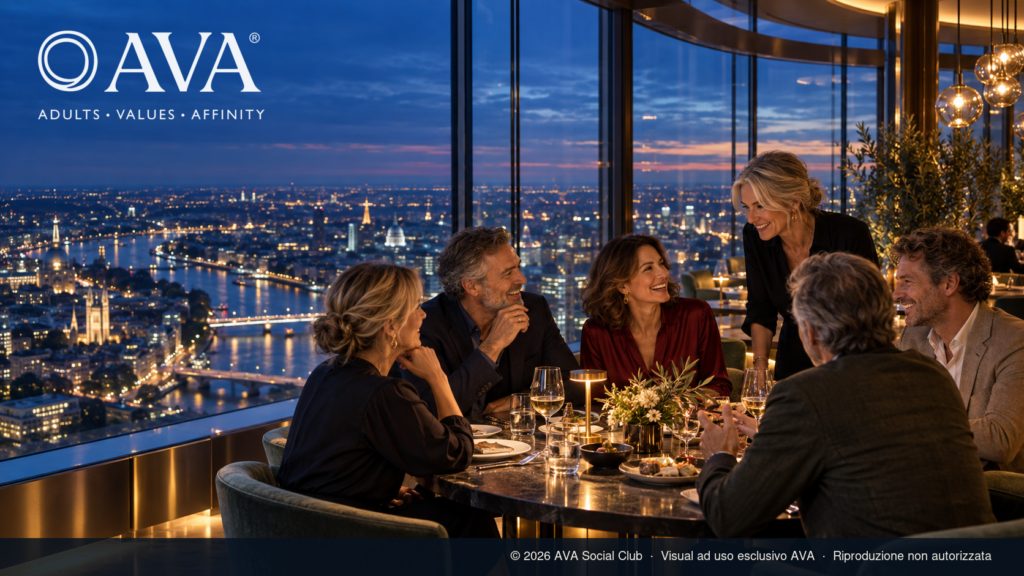 Gruppo di adulti tra i 50 e i 60 anni conversa in un ristorante panoramico, esempio di third place per la socialità adulta.